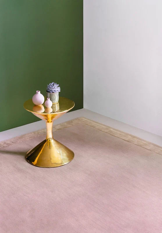 Blush hand-tufted rug corner detail with brass side table and pink accents