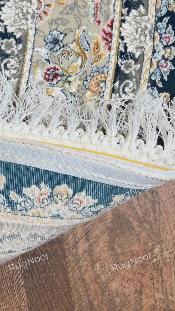 Folded Fawaniya rug displaying the patterned surface, ornate edge, and ivory fringe.