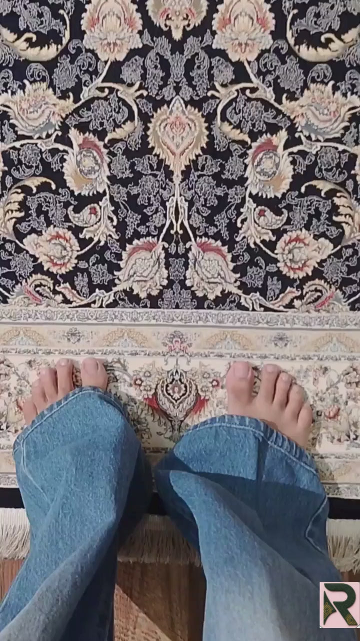 Close-up of the Zarniva traditional floral carpet showing intricate ivory scrolling vines, symmetrical floral motifs and rust, gold and pale blue accents on a navy background.