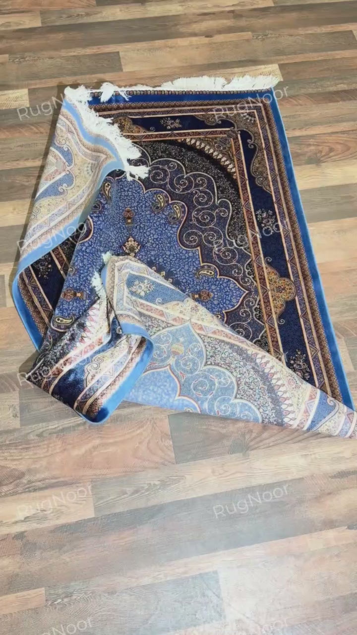 Yasamin folded rug showing its blue and gold pattern, underside, and ivory fringe.
