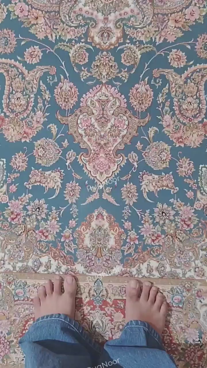 RugNoor Ruvaira 5x7 traditional floral carpet with a teal-blue centre, ornate floral medallion, rust-red border, ivory and blush-pink details, and decorative fringe.