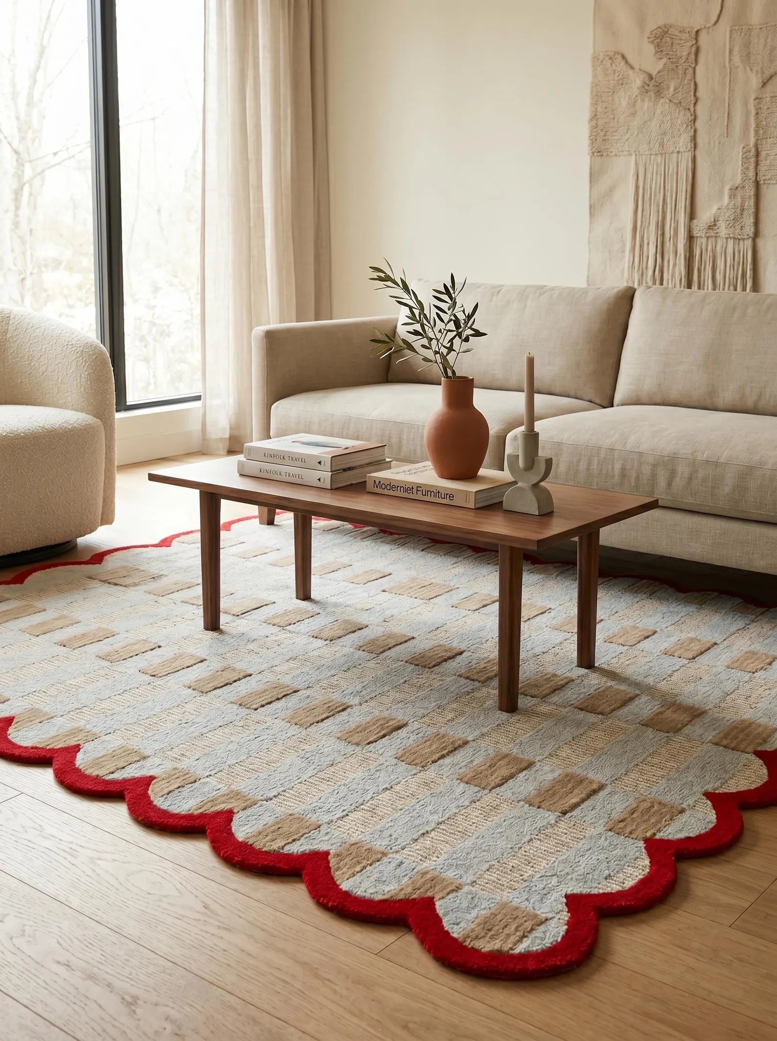 A styled living room scene featuring a patterned area rug with a scalloped red border, placed under a wooden coffee table in front of a beige sofa.