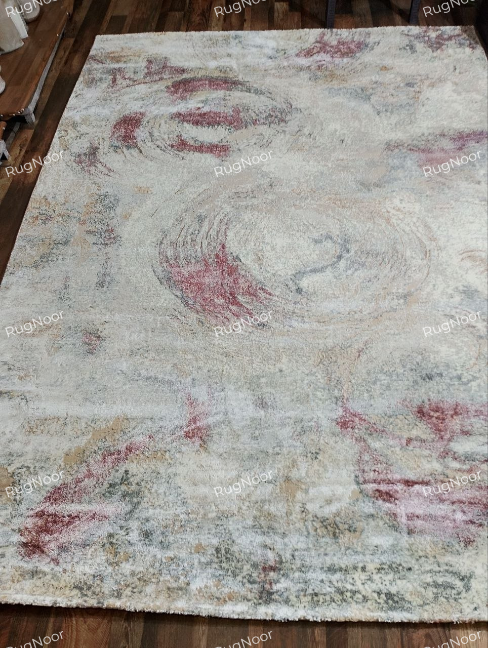 Full front view of the 8 × 11 ft Rovelle modern abstract rug showing its complete swirling pattern in ivory, beige, dusty rose and muted brown.