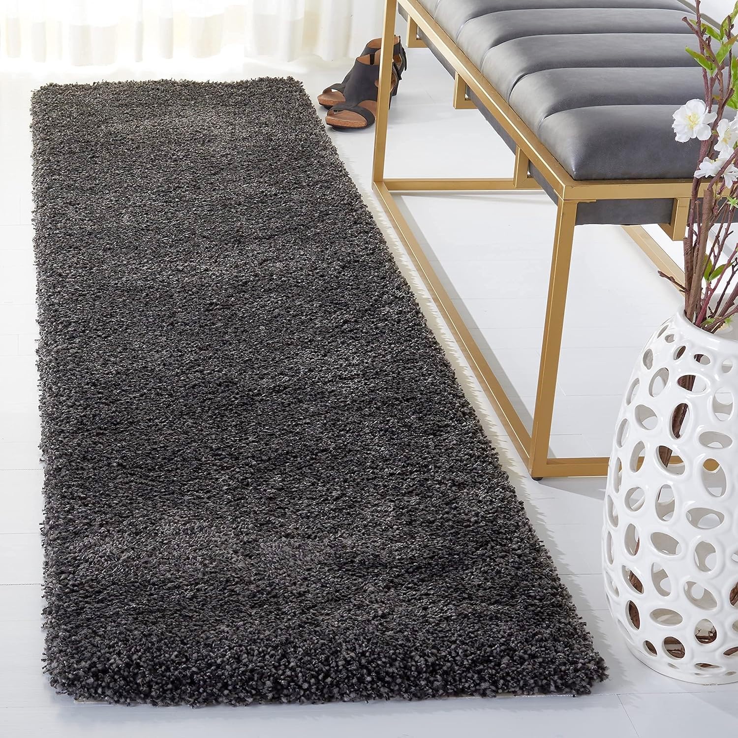 Dark gray shaggy rug in a living room setting with a bench and decorative items.