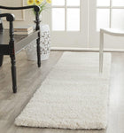 White ivory shaggy rug on a wooden floor with chairs and a table in a room.