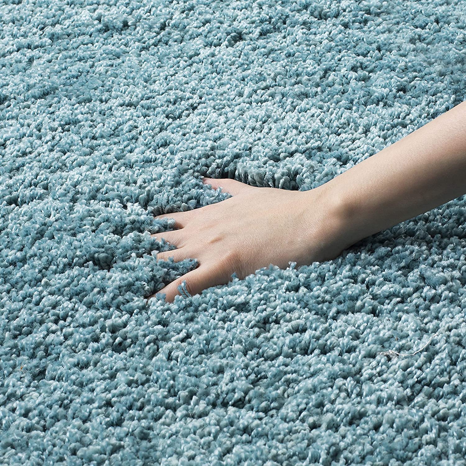 Hand touching a blue textured carpet