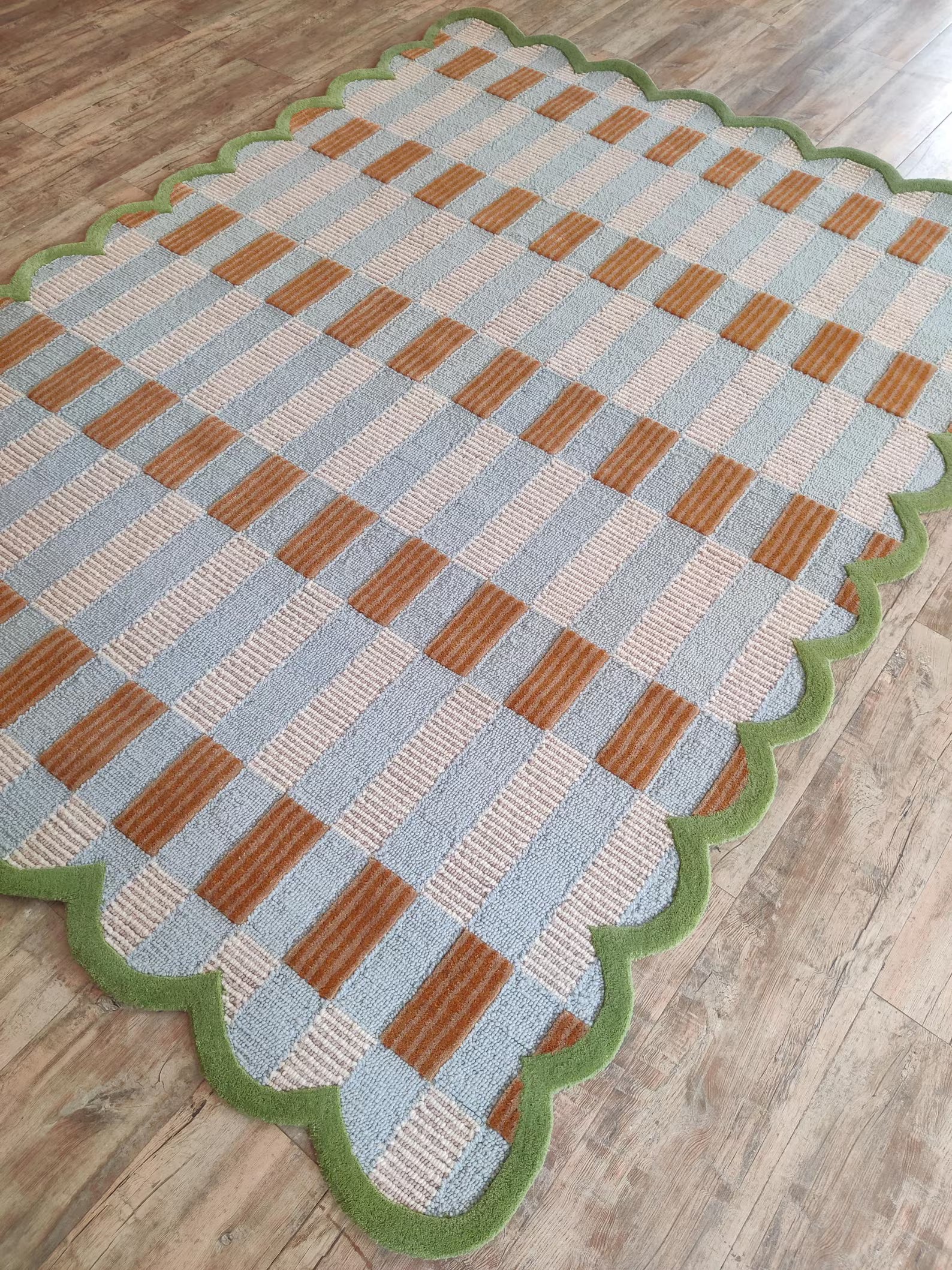 Checkered rug with brown, blue, and green pattern on a wooden floor