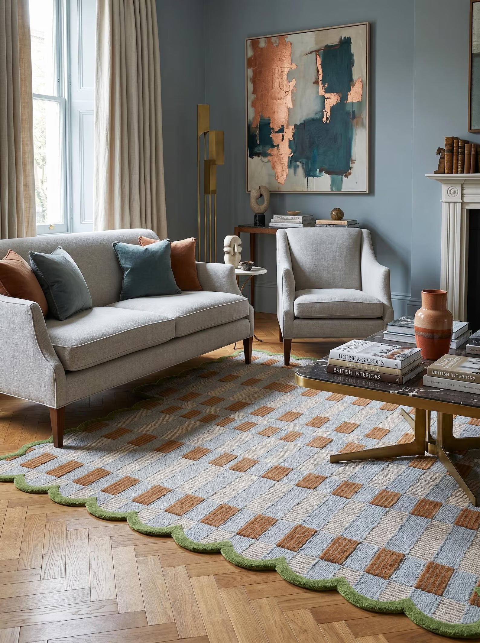 A styled living room featuring a large patterned area rug with a scalloped green border, laid out on a wooden parquet floor. The rug has a geometric basketweave design in light blue, beige, and brown, bordered by green.