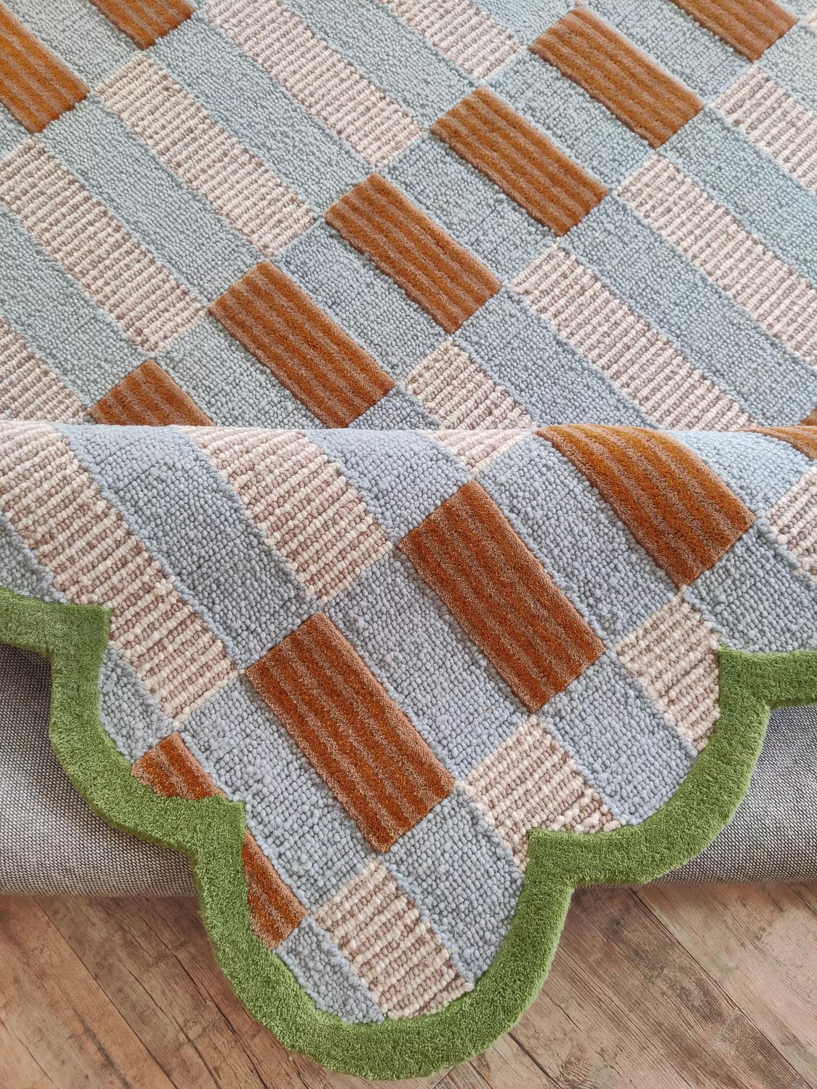 Patterned rug with brown, beige, and green colors on a wooden floor.