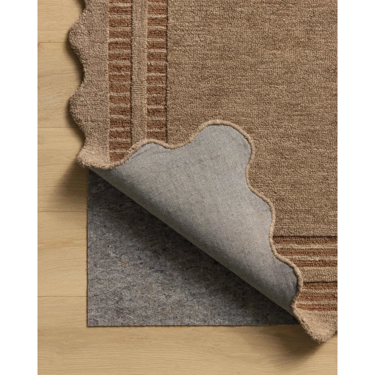 Brown textured rug with gray underlay on a wooden floor