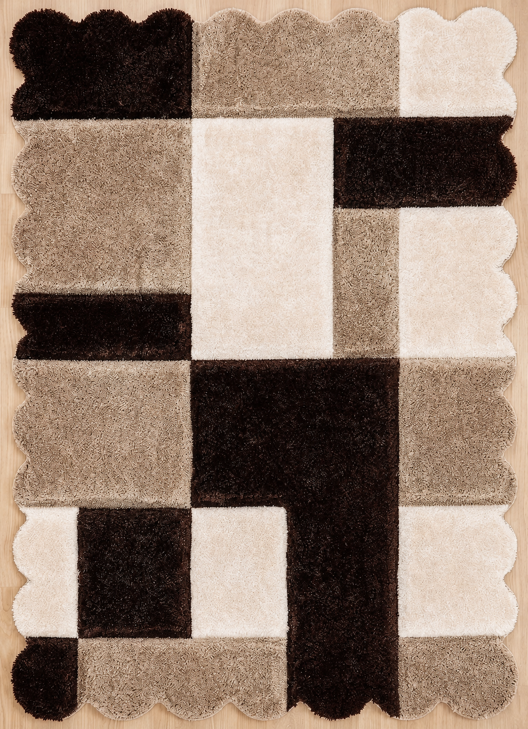 A rectangular area rug with a geometric patchwork design in dark brown, beige, and cream, featuring scalloped edges and a plush texture.