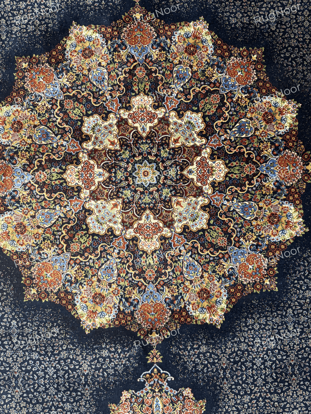 Close-up of a small decorative floral motif on the navy field beside part of the larger medallion by RugNoor
