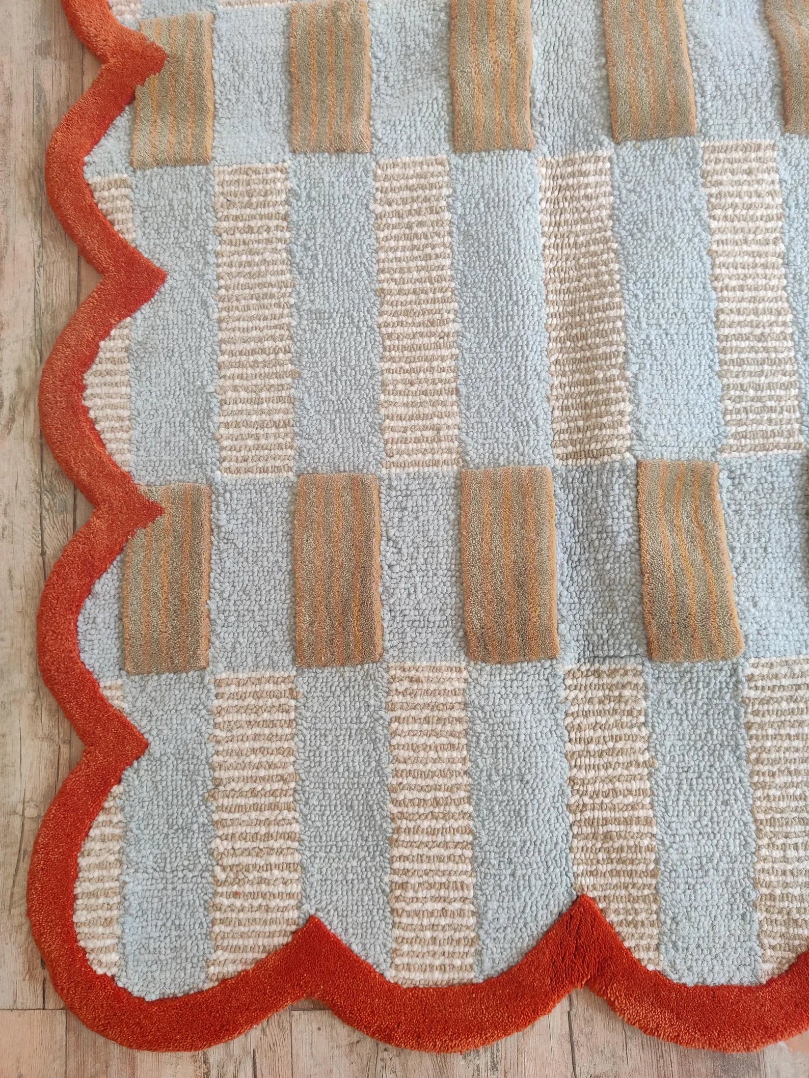 Patterned rug with red and beige geometric design on a wooden floor