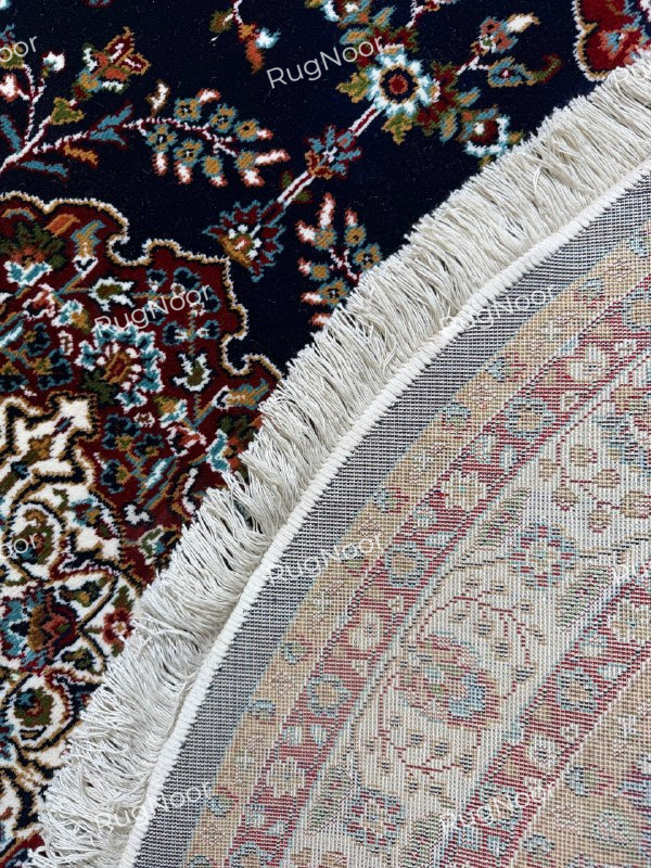 Close-up of Tiraj round navy floral rug showing intricate motifs, ivory fringe, and patterned backing - RugNoor