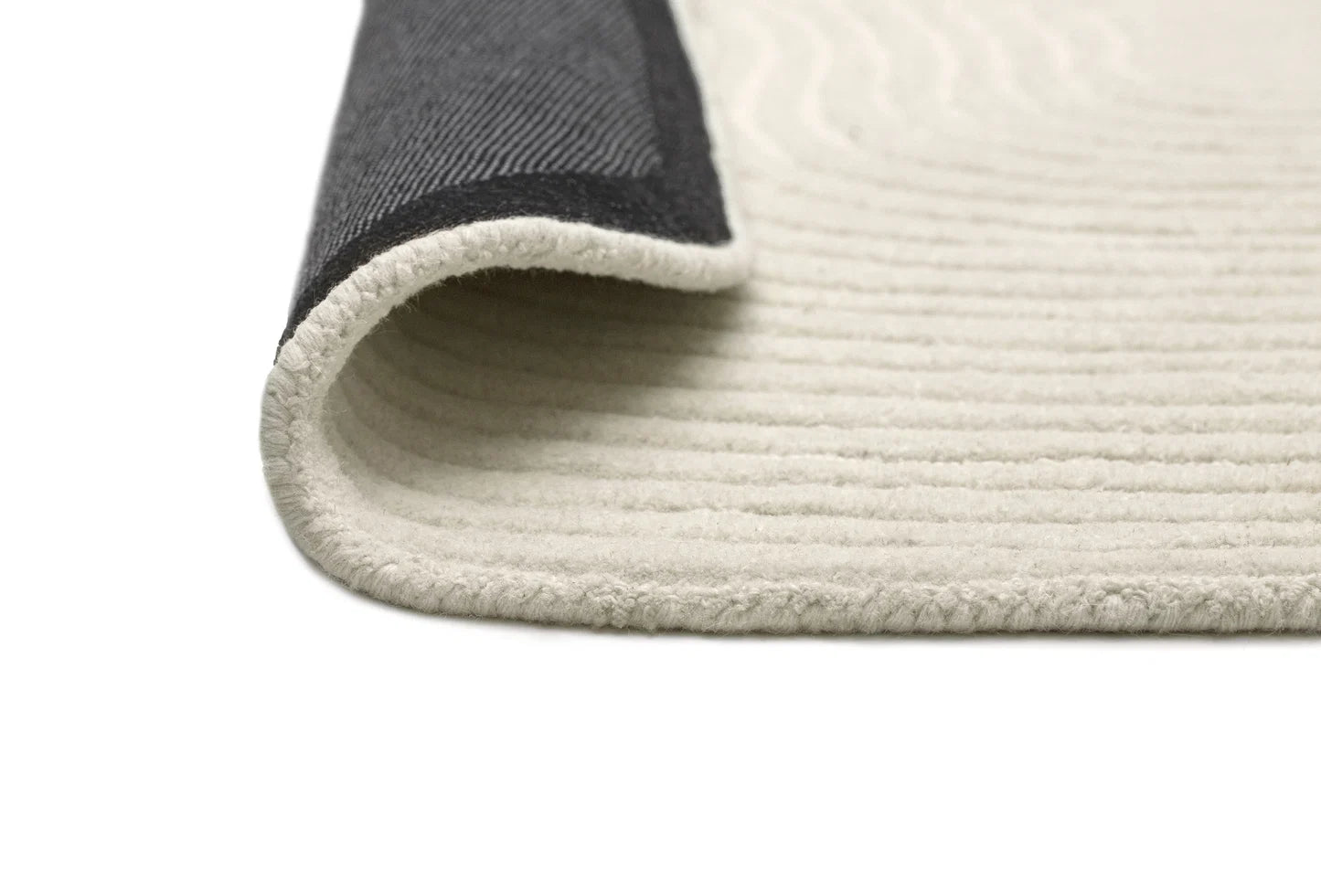 Close-up of a textured rug corner with a neutral color palette.