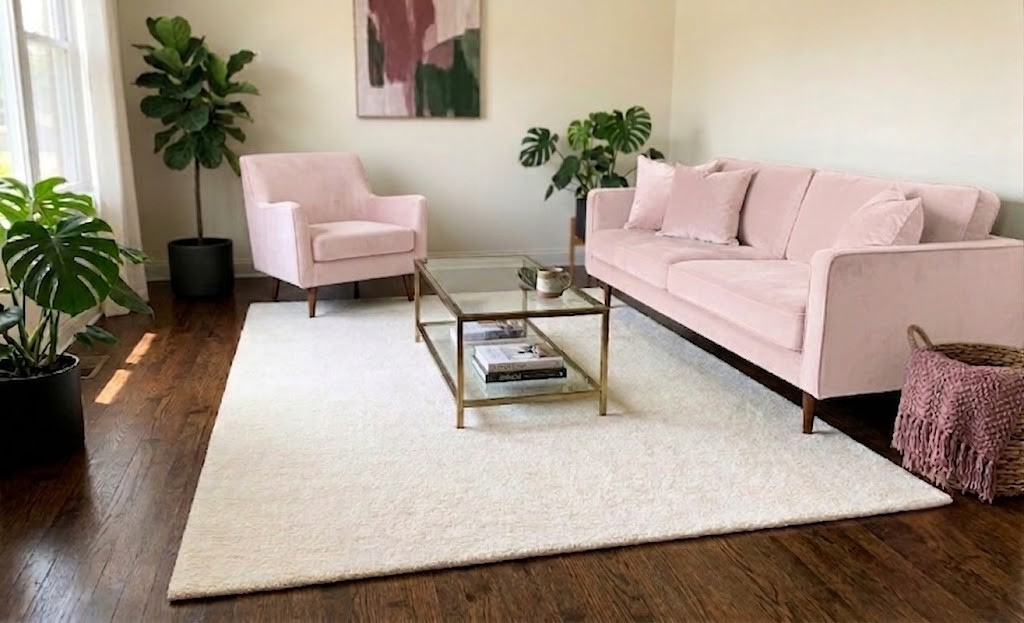 White hand-tufted area rug styled in modern living room with pink sofa and armchair