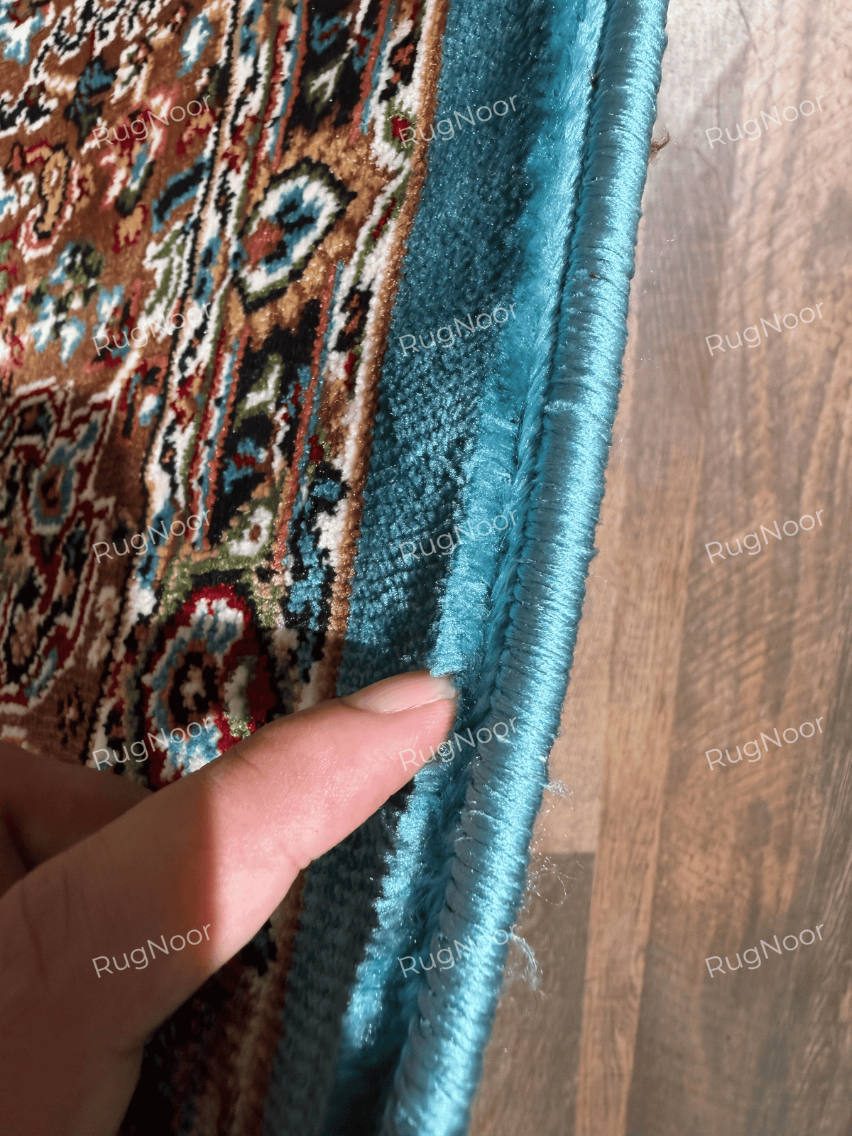 Close-up of turquoise rug edge finishing and bound seam beside the carpet pile - Zukhruf RugNoor