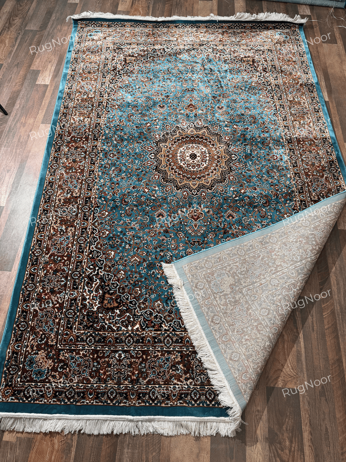 Turquoise traditional rug with a folded corner showing its pale patterned underside and fringe - Zukhruf RugNoor