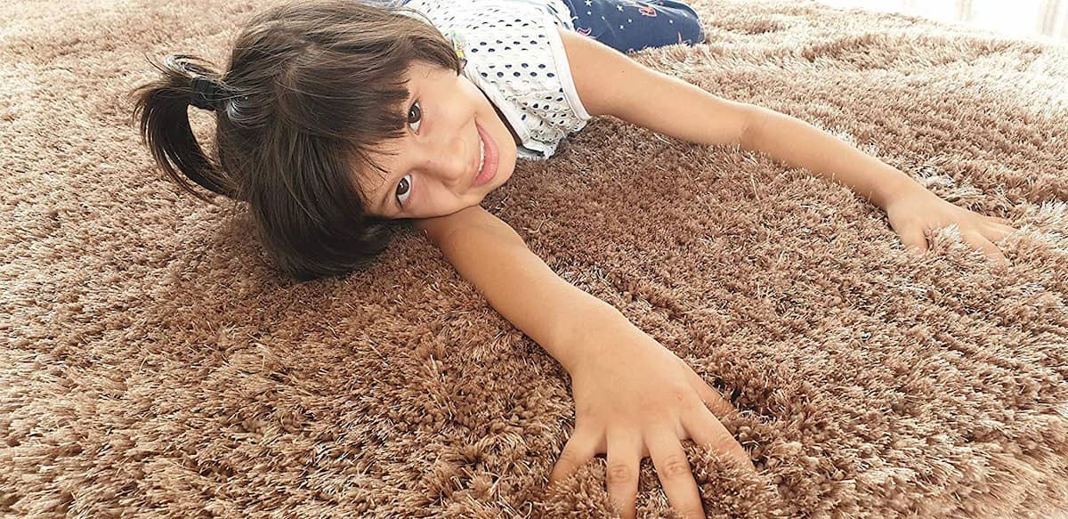 Child lying comfortably on soft beige shag rug - RugNoor