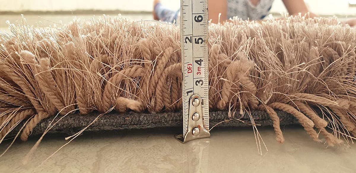 Tape measure showing 2 inch pile height of beige shag rug - RugNoor