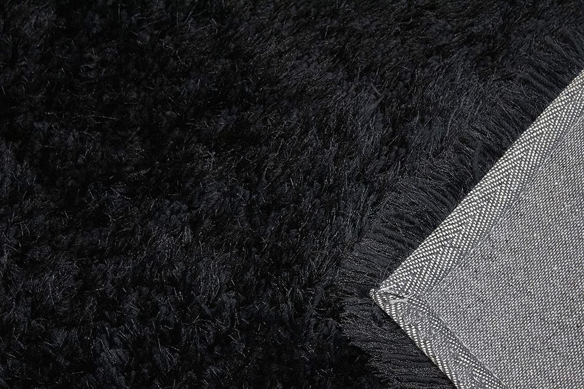 Black shag rug corner folded to show woven backing - RugNoor