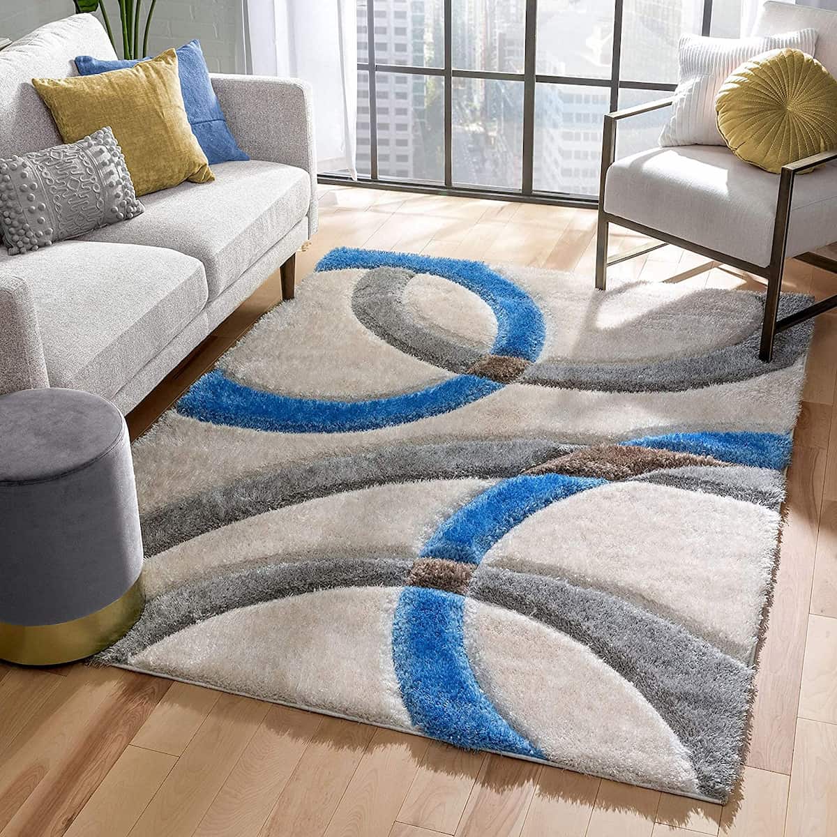 A RugNoor's shaggy rug with blue, grey, and white colors, placed on a wooden floor in a living room setting, complementing the decor.