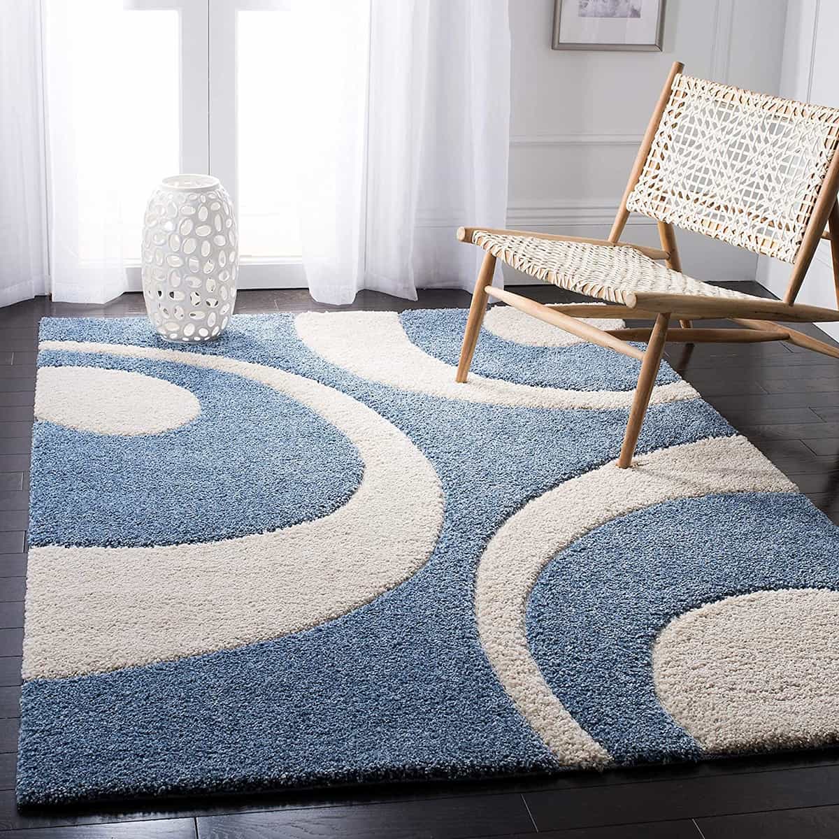 A shaggy rug with blue and white colors, placed on a floor in a room with a chair and a window in the background - RugNoor