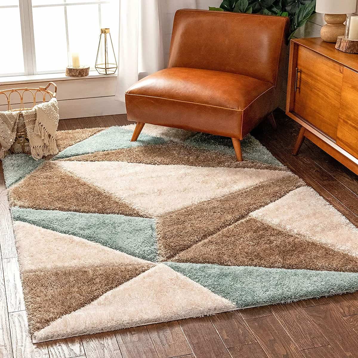 A RugNoor shaggy rug with diamond-shaped design in aqua and brown colors, placed on a wooden floor under a leather chair and next to a wooden cabinet.