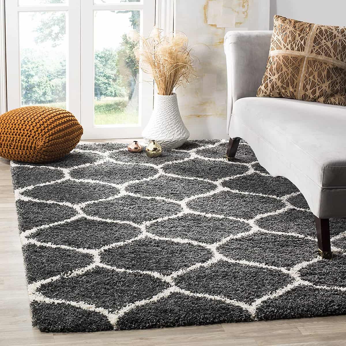 A charcoal grey and ivory geometric pattern microfiber shaggy rug on a floor, with furniture arranged on top of it.