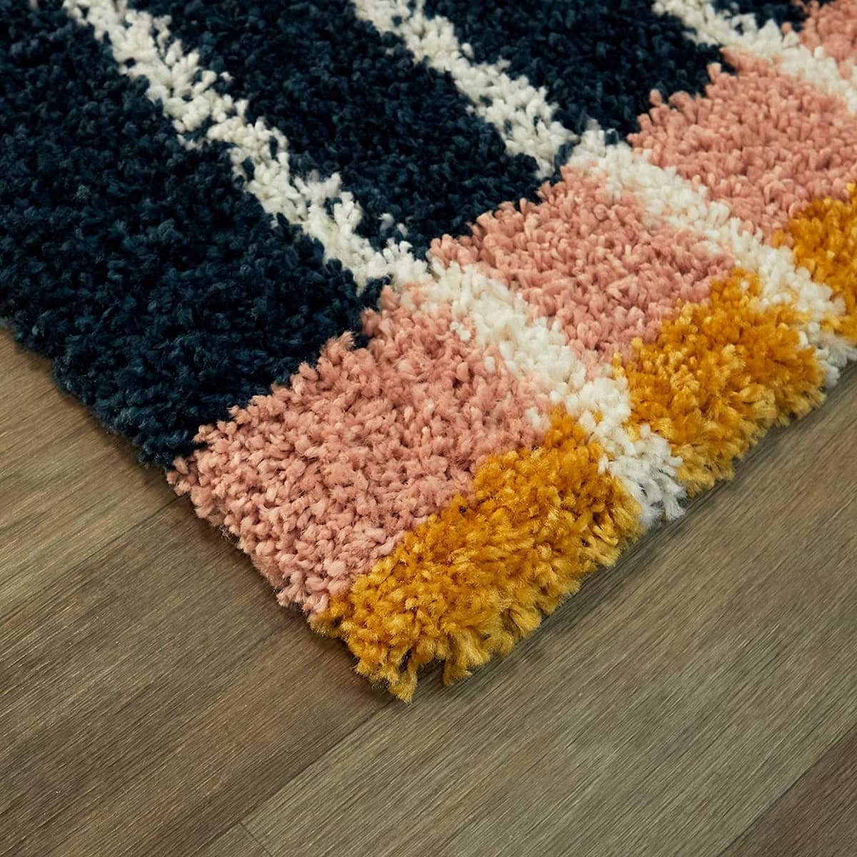 Corner close-up of navy, pink, yellow striped shag rug pile texture, RugNoor fluffy carpet