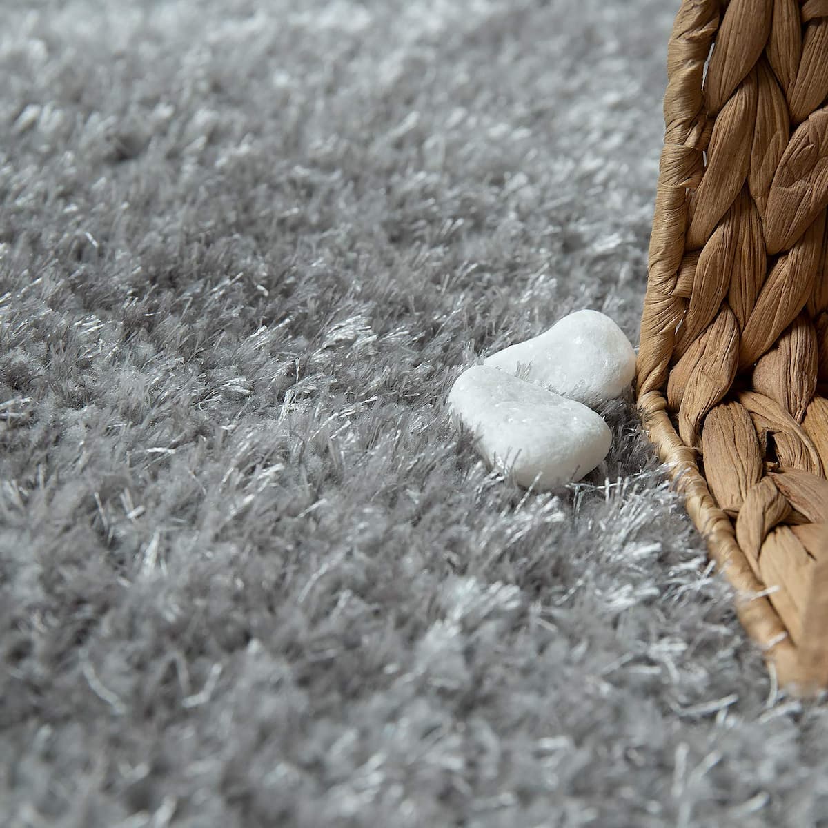 Smooth white pebbles set on a dark grey shag rug beside a rattan basket