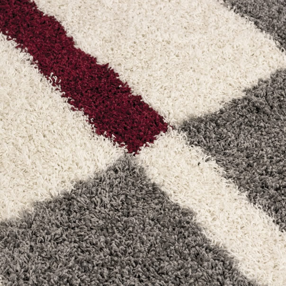 Micro close-up of a maroon accent stripe on a white and grey shaggy rug