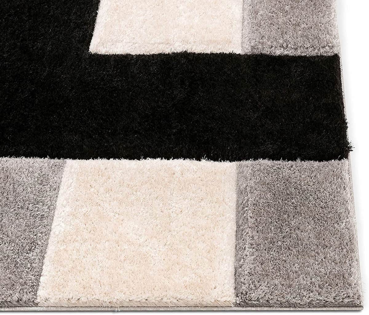 corner of a block design shaggy carpet in white, black and silver color