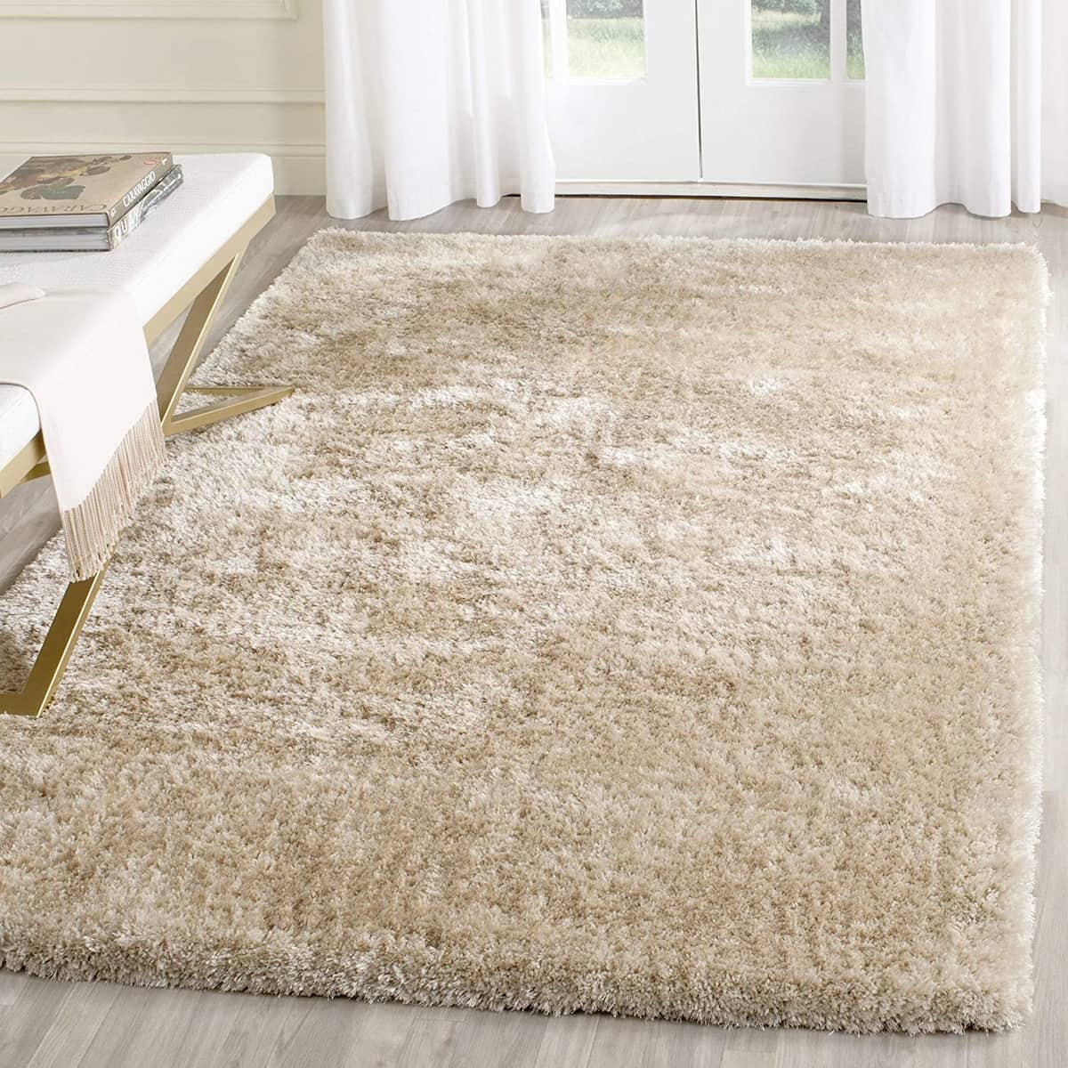 A cream-colored shaggy rug on a light-colored floor, with a white door and curtains in the background - RugNoor