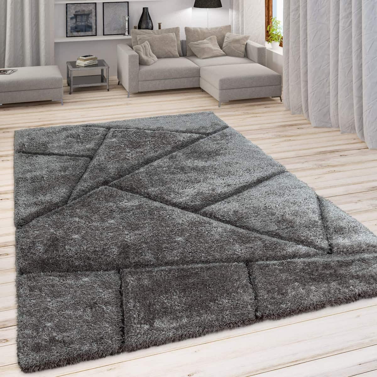 A RugNoor's dark grey shaggy rug with geometric patterns placed on a wooden floor in a living room setting.