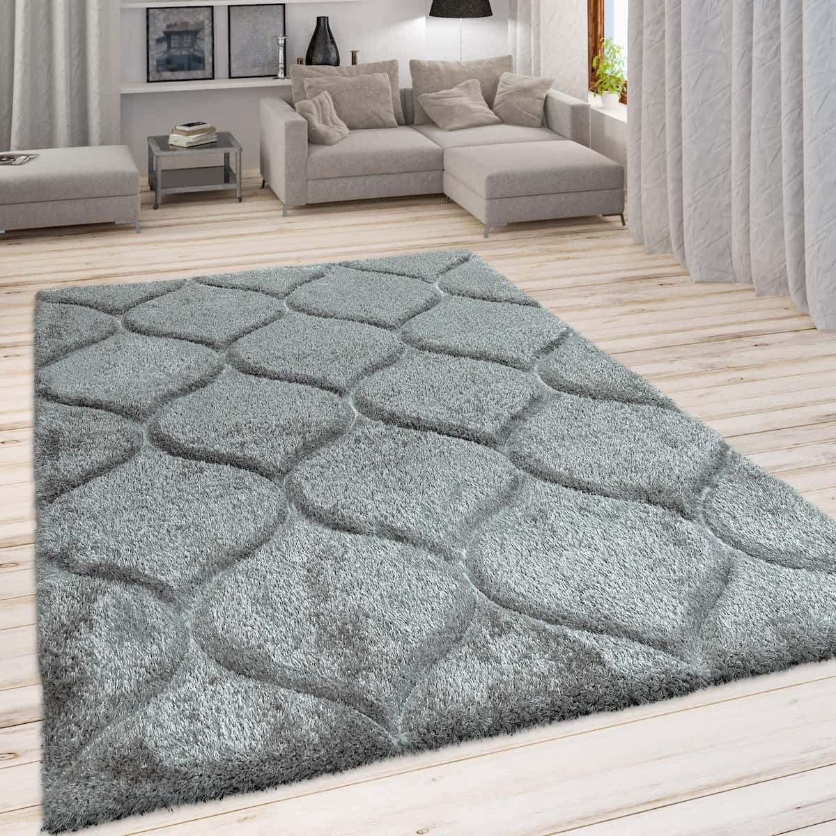 A RugNoor's dark grey shaggy rug with Ogee trellis pattern placed on a wooden floor in a living room setting with furniture.