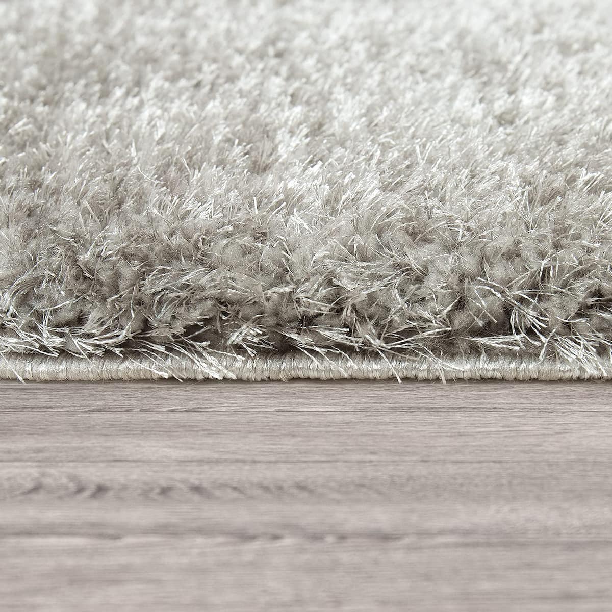 RugNoor's Silvery grey shag fibers meeting a light wood floor edge