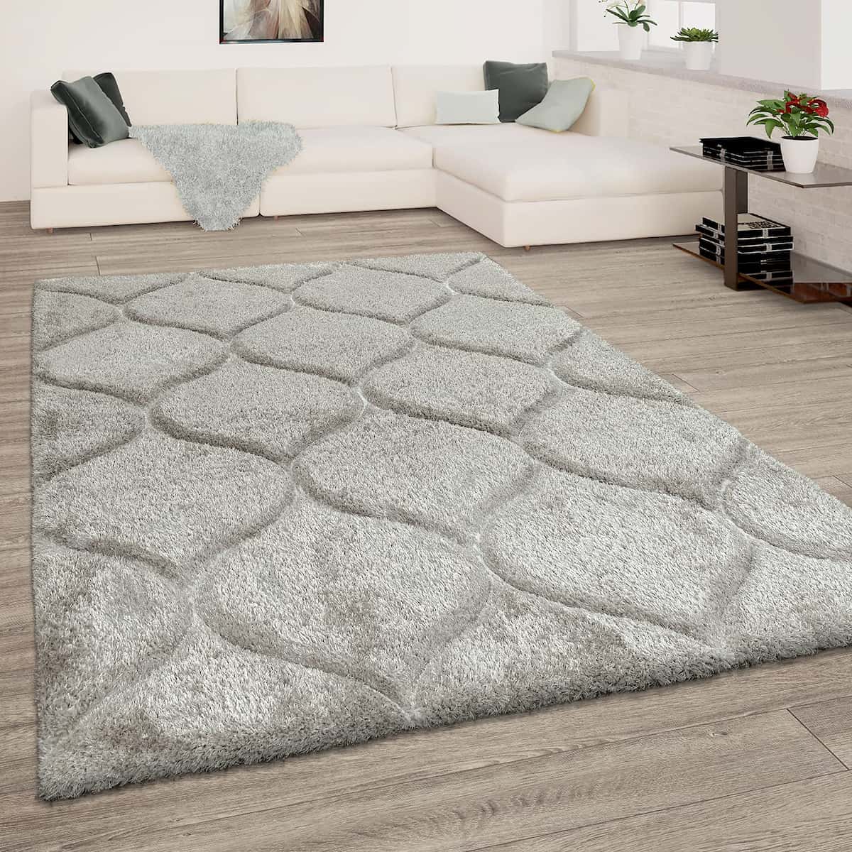 A RugNoor's grey shaggy rug with Ogee trellis pattern placed on a wooden floor in a living room setting, complementing the neutral color scheme.