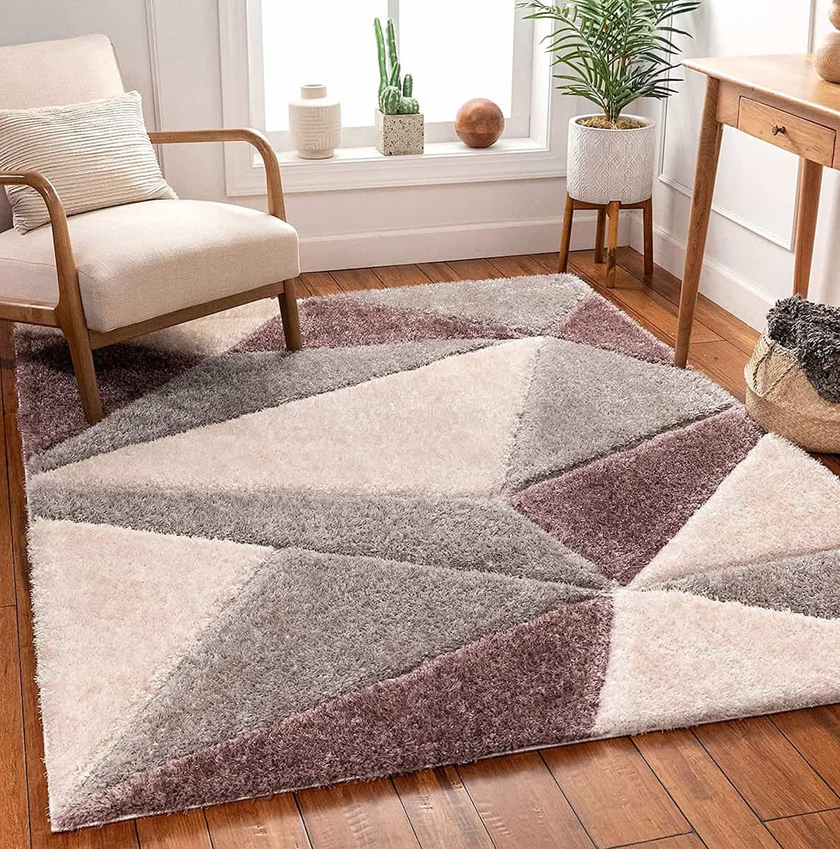 A RugNoor's shaggy rug with a diamond pattern in grey and cream colors, placed on a wooden floor under a window with a chair and a plant.