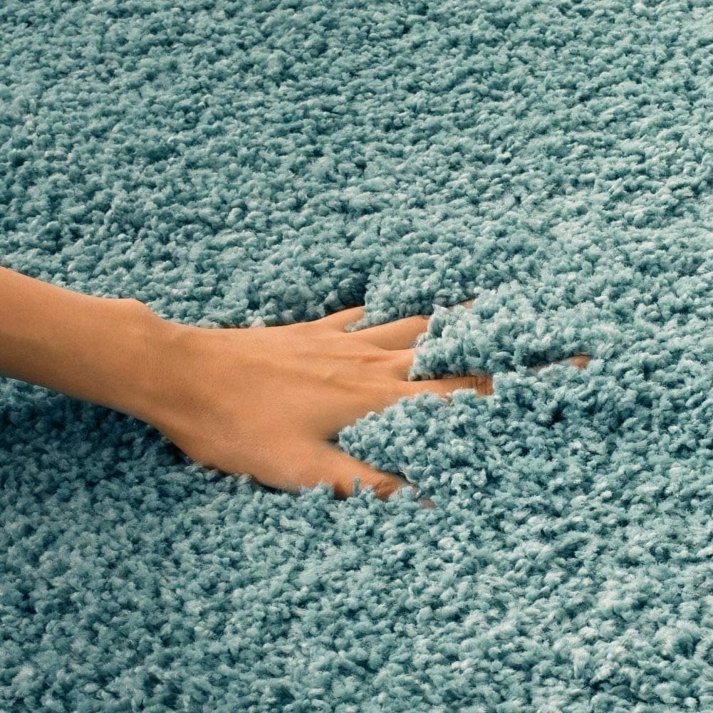 Hand sinking into thick light blue shag rug pile - RugNoor