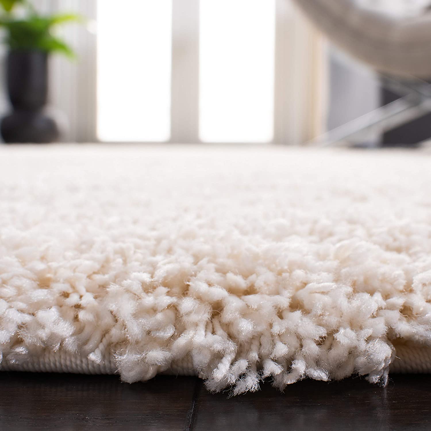 Ivory shag rug edge close-up on dark wood floor - RugNoor
