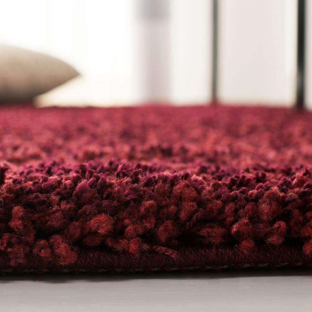 Maroon shag rug edge close-up with cushion in background - RugNoor