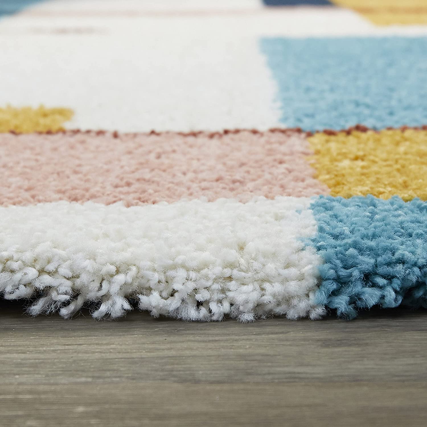 RugNoor's side profile of a color-blocked shaggy carpet showing white, pink and blue design