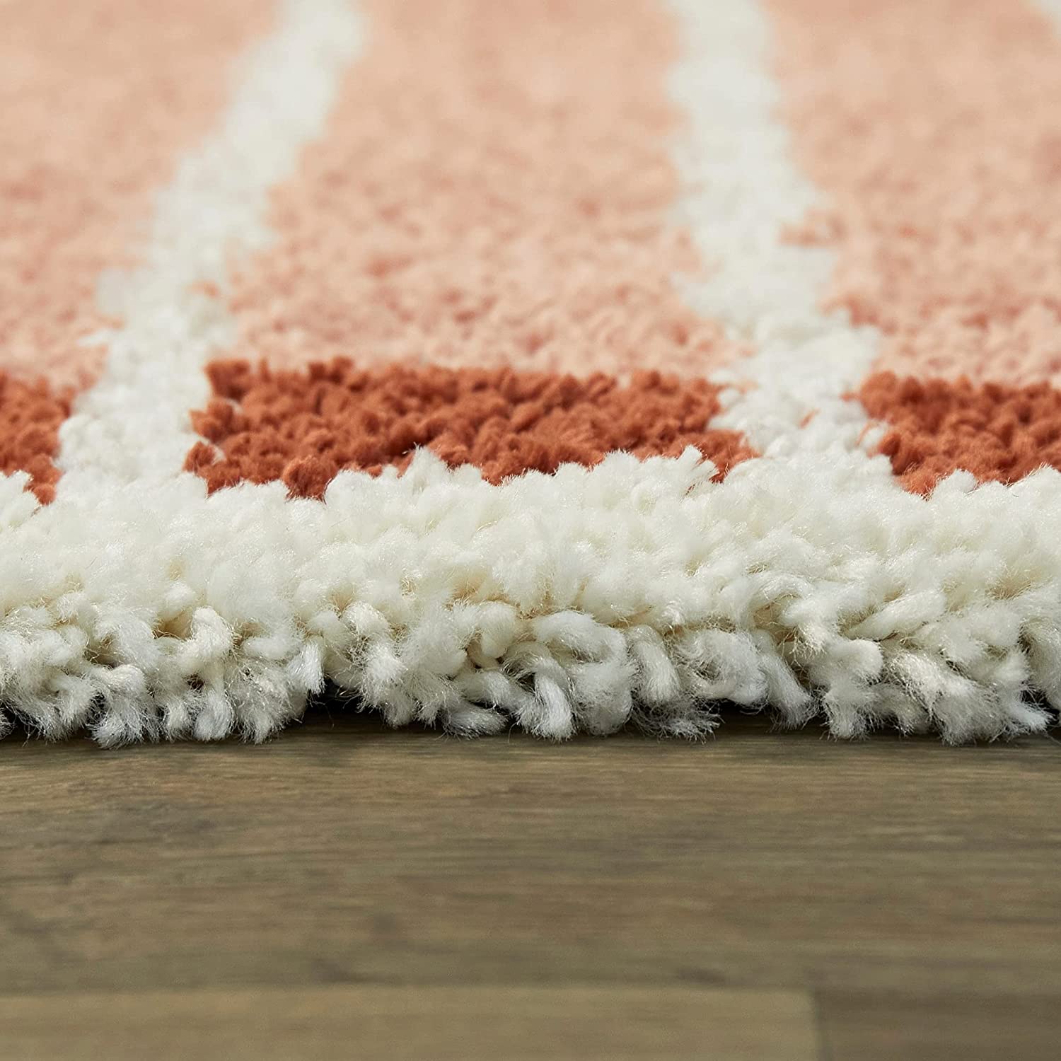 Ground-level close-up of pink white rust arch pattern shag rug pile, RugNoor soft carpet