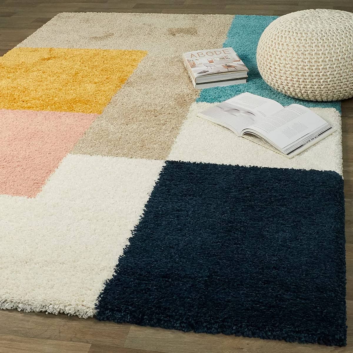 Pink teal navy patchwork shag rug styled in living room with pouf and books, RugNoor fluffy carpet
