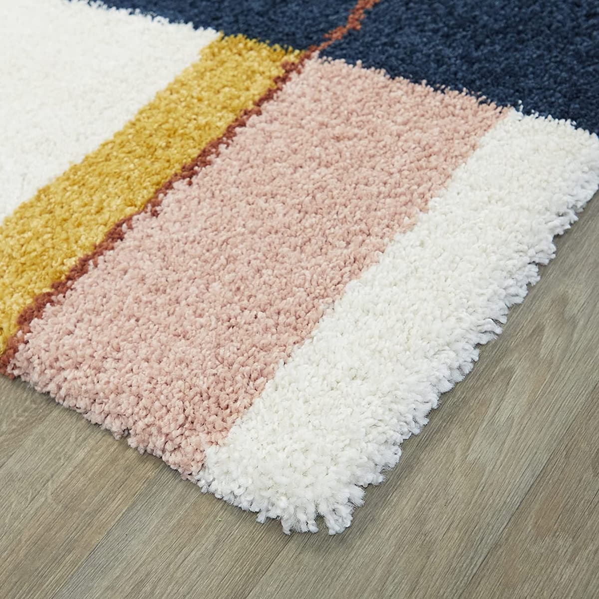 Angled close-up of RugNoor's color-blocked carpet edge on a wood floor