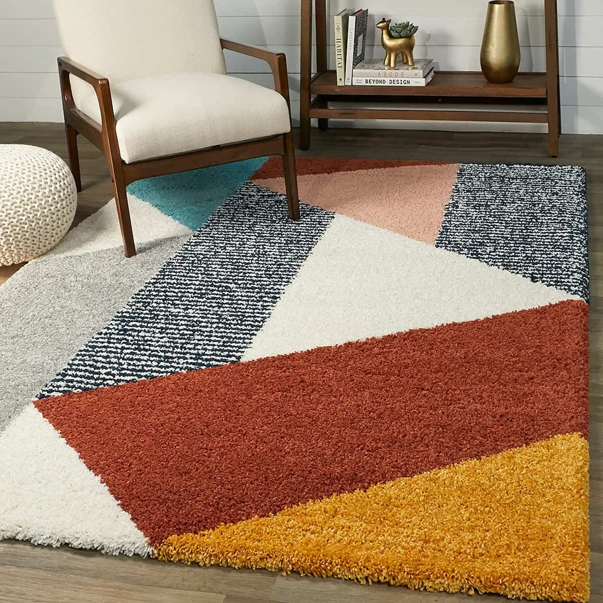 RugNoor's shaggy rug with a geometric pattern in multiple colors placed on a wooden floor, with a chair and a side table in the background.