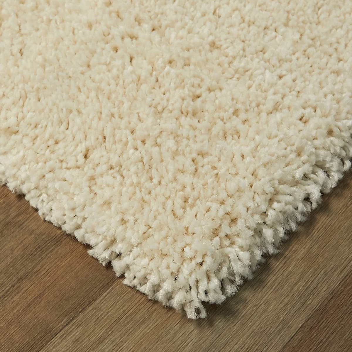 RugNoor corner close-up cream white shag rug pile, soft fluffy carpet on wooden floor
