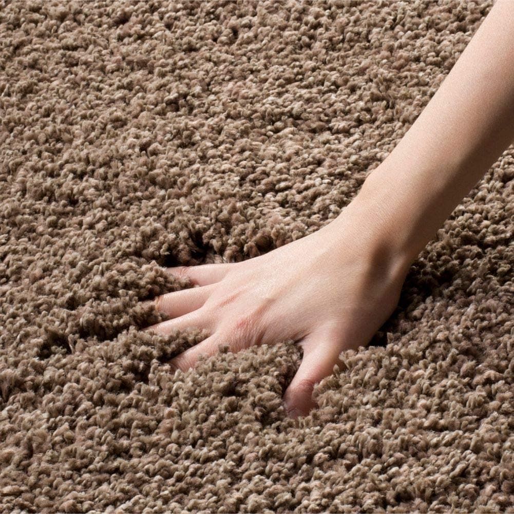 Hand sinking into thick taupe shag rug pile - RugNoor