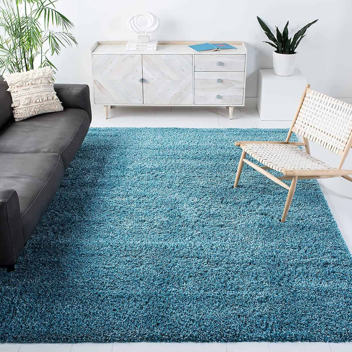 A turquoise microfiber shaggy rug in a room with a gray sofa, white chair, and wooden cabinet - RugNoor